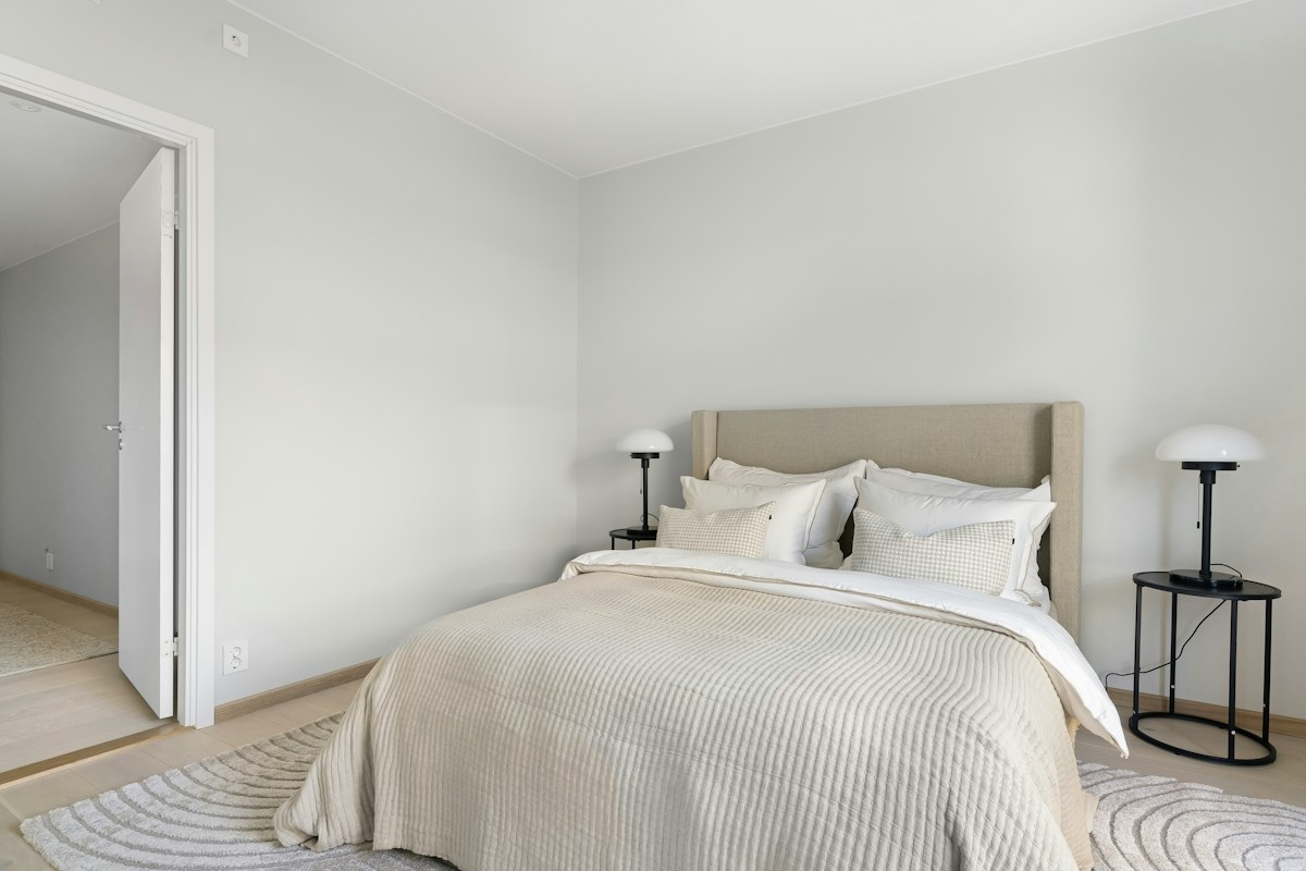A neatly prepared bedroom with crisp bedding and soft neutral furnishings